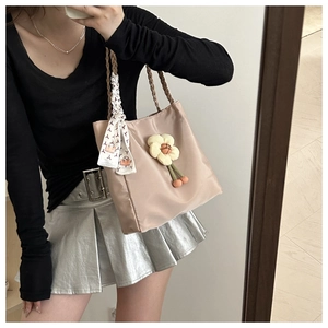 Detail of a nylon tote bag with floral pendant and patterned silk scarf on handle
