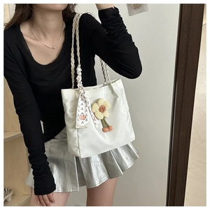 Detail of off-white tote bag with woven straps, yellow flower charm and silk scarf wrap