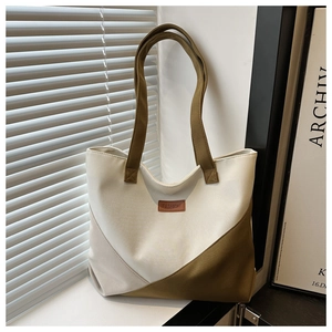 Detail of color-block canvas tote bag featuring a leather FASHION label on window sill