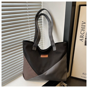 Detail of color-block canvas tote bag showing the fashion leather tag and strap texture