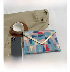 Detail view of colorful geometric triangle patterned envelope clutch with gold V-hardware