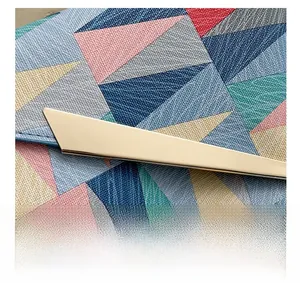 Detail of colorful geometric pattern stitching and polished gold buckle on leather clutch