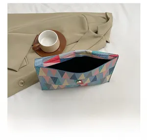 Detail view of colorful geometric pattern handbag with metal snap button and inner capacity