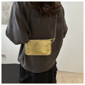 Close-up of golden metallic textured crossbody bag with bead edges and silver chain
