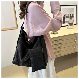 Dettaglio di una borsa hobo nera con trama marmorea e portamonete coordinato sulla spalla