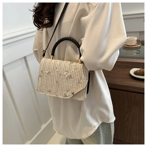 Dettaglio della borsa in paglia beige con ricami floreali rosa e manici neri