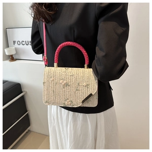 Dettaglio borsa in paglia beige intrecciata con ricami floreali e manici rosa acceso