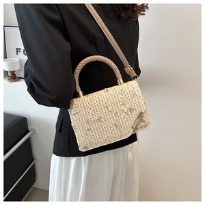 Ricamo dettagliato con fiori verde chiaro su una borsa a tracolla in paglia intrecciata