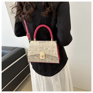 Détail d'un sac bandoulière en paille avec broderie florale et anse rose porté par un mannequin