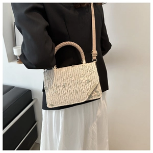 Dettaglio della borsa quadrata intrecciata beige con ricami floreali e tracolla