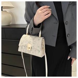 Détail du sac en paille tissée crème avec broderies florales et fermoir doré