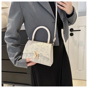 Détail du sac bandoulière en paille tissée avec broderie florale et fermoir doré