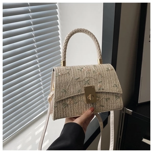 Détail d'un sac en paille tissé avec broderie florale et fermoir en métal doré