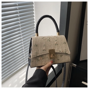 Détail du sac en paille avec broderie florale et fermoir en métal doré de luxe