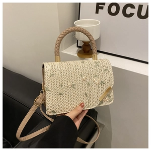 Dettaglio ravvicinato dei ricami floreali e della trama di paglia della borsa beige
