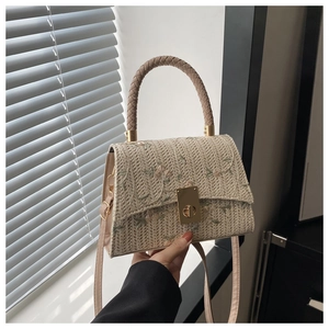 Détail du sac bandoulière beige tissé avec broderie florale et fermoir métallique doré
