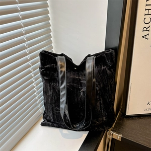 Minimalist black velvet tote bag with leather handles in a modern interior setting