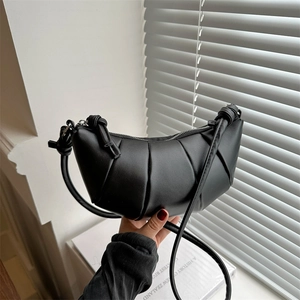 Modern black croissant shoulder bag with pleated faux leather and knot strap detail