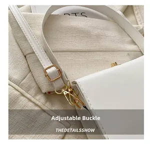 Détail de la boucle métallique réglable et de la bandoulière en cuir du sac blanc