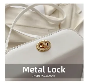 Détail du fermoir doré en métal sur sac en cuir blanc avec coutures précises