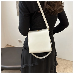Détail d'un sac à bandoulière en similicuir blanc avec fermoir rotatif doré sur modèle