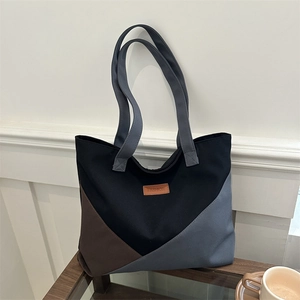 Large color-block canvas tote bag with fashion tag on a minimalist side table