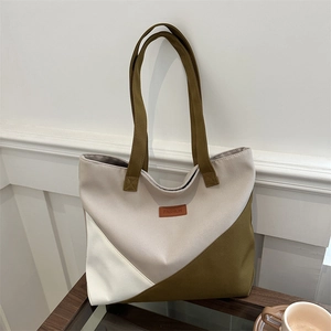 Canvas tote bag with green color block design and leather patch on wooden desk