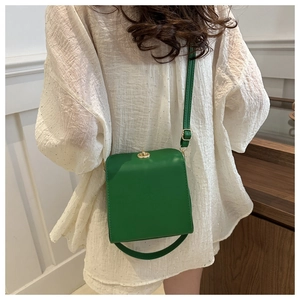 Gros plan d'un sac bandoulière vintage vert avec fermoir rotatif doré en forme de cœur