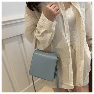 Détail du sac bandoulière bleu clair en forme de boîte avec fermoir rotatif doré