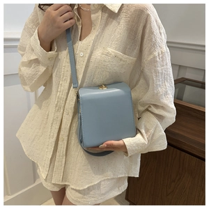 Mannequin portant un petit sac bandoulière bleu clair en cuir avec fermoir doré