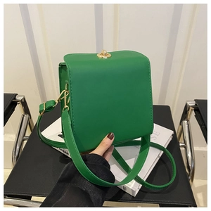 Détail du sac bandoulière vert avec fermoir rotatif doré et texture en cuir lisse