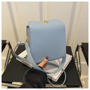 Détail du sac carré bleu clair avec fermoir rotatif en métal doré et bandoulière large