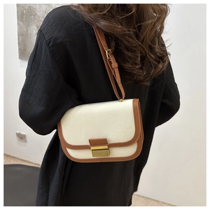 Detail of canvas leather crossbody bag with golden metal buckle on model's back