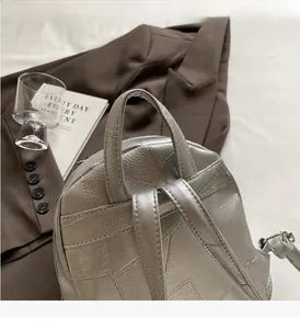 Detailansicht des verstärkten Griffs und der Nähte am silbernen Metallic-Patchwork-Rucksack