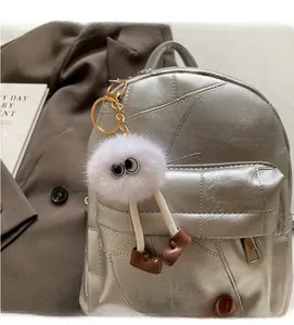 Nahaufnahme eines weißen Plüschmonsters mit großen Augen an einem silbernen Rucksack
