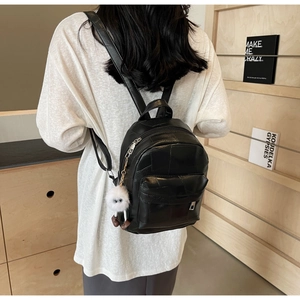 Détail d'un mini sac à dos en similicuir noir avec fermetures éclair argentées