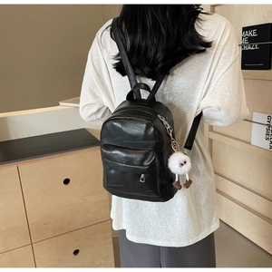 Vue détaillée du mini sac à dos en similicuir noir avec motif patchwork et breloque en peluche