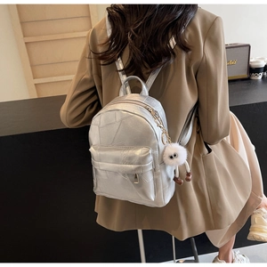 Details eines silbernen Metallic-Rucksacks mit geometrischer Textur und Plüsch-Anhänger