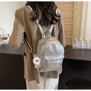 Détail du sac à dos métallique argenté avec coutures géométriques et grigri en peluche