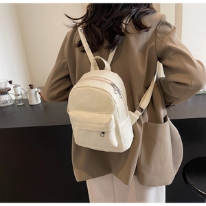Close-up of cream mini backpack with geometric stitching on textured synthetic leather