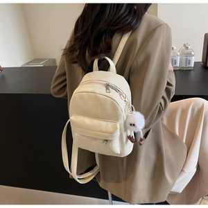 Mini sac à dos crème en similicuir avec surpiqûres croisées et pendentif en peluche blanc
