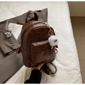 Details des dunkelbraunen PU-Rucksacks mit Litschi-Struktur, Plüsch-Anhänger und Metallzipper