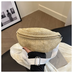 Detail of woven straw fanny pack with natural texture and adjustable white strap