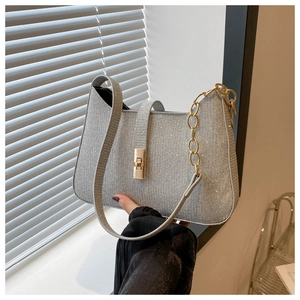 Gros plan du sac en argent pailleté avec fermoir rotatif doré et bandoulière chaîne