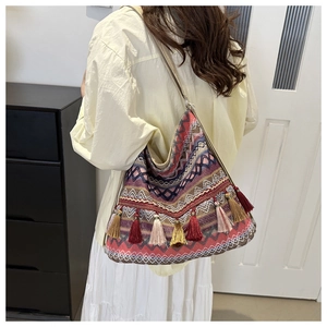 Detail of bohemian knit tote bag showing colorful geometric patterns and long tassels