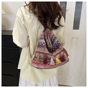 Detail of bohemian woven backpack with red ethnic pattern and colorful tassel charms