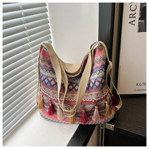 Detailed view of bohemian woven tote bag with ethnic patterns and colorful fringe tassels