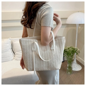 Detail of hand-woven beige tote bag showing texture and white leather handle