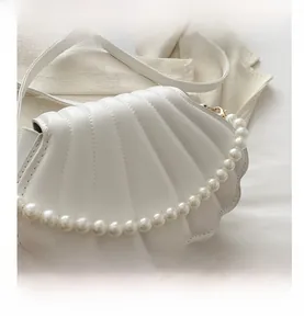 Dettaglio borsa a conchiglia bianca con manico di perle e trama trapuntata elegante
