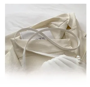 Dettaglio borsa trapuntata bianca con manico di perle e sottile tracolla in pelle morbida